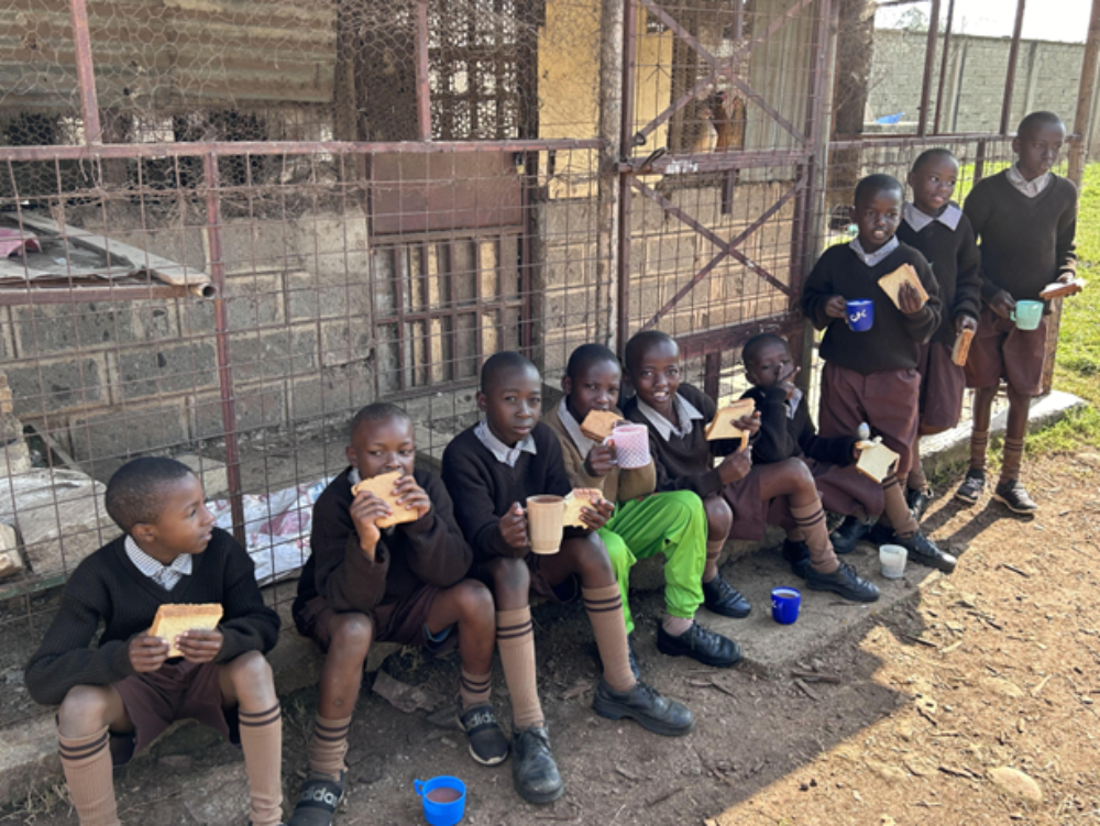 Amani School students eating Amani School students eating sandwiches in the shade