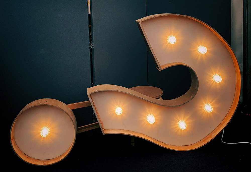 A electronic question mark sign is lit up in this photo illustration. (Unsplash/Jon Tyson)