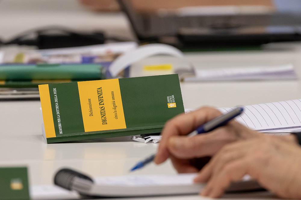 Cardinal Víctor Manuel Fernández, prefect of the Dicastery for the Doctrine of the Faith, takes notes during a news conference to present Dignitas Infinita, a copy of which is nearby, at the Vatican press office April 8, 2024. (CNS/Pablo Esparza)