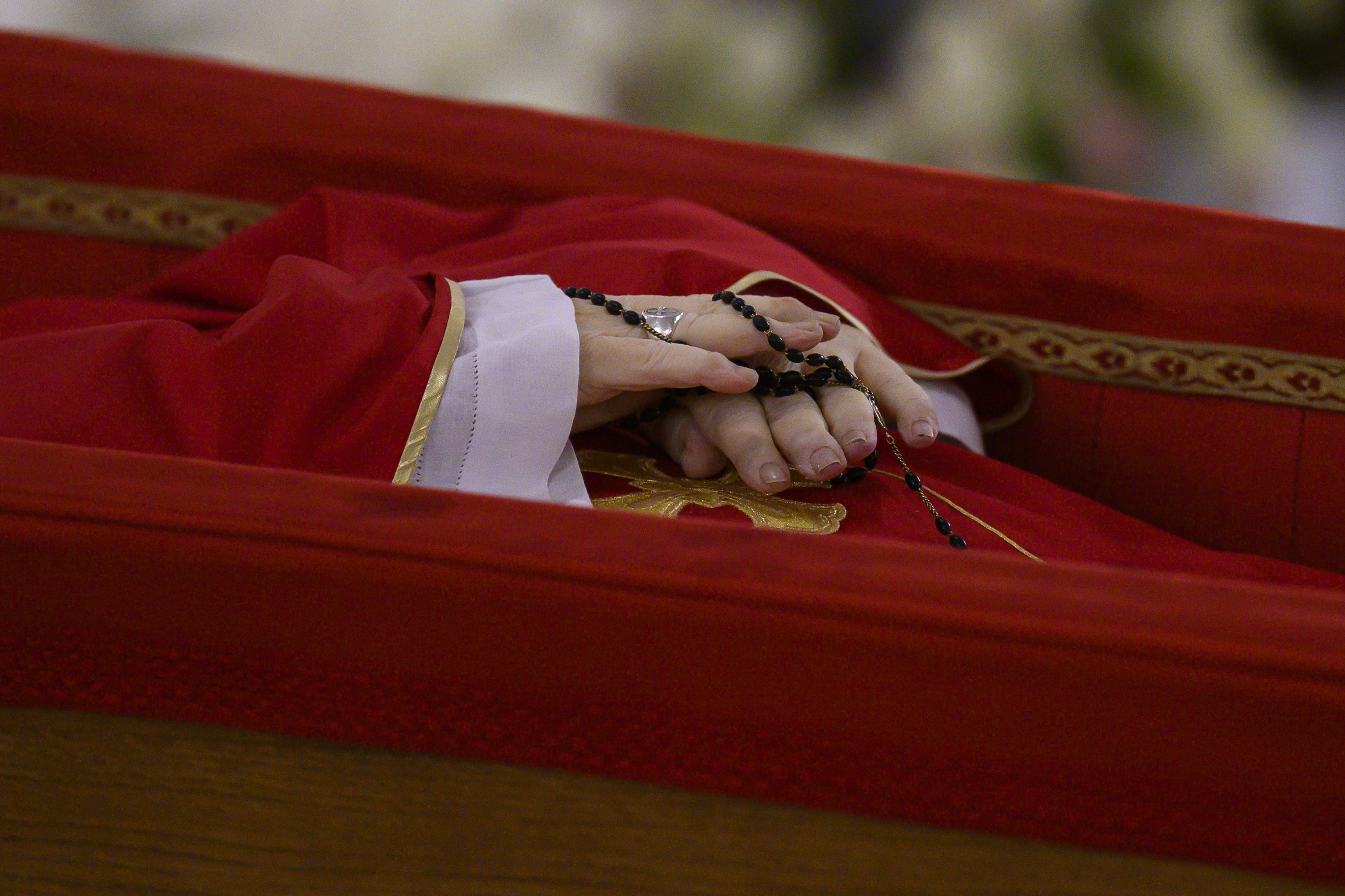 The hands of Pope Francis, holding a rosary, are seen as he lies at rest in his coffin in the chapel of his residence