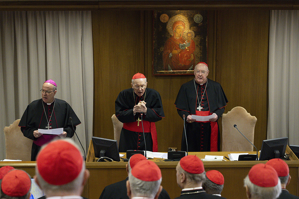 Cardinal Giovanni Battista Re, dean of the College of Cardinals, center, leads cardinals in prayer during their first general congregation April 22, 2025, in the Vatican Synod Hall. To Cardinal Re's left is U.S. Cardinal Kevin Farrell, chamberlain of the Holy Roman Church, and to the left is Archbishop Ilson Montanari, secretary of the College of Cardinals. (CNS/Vatican Media)