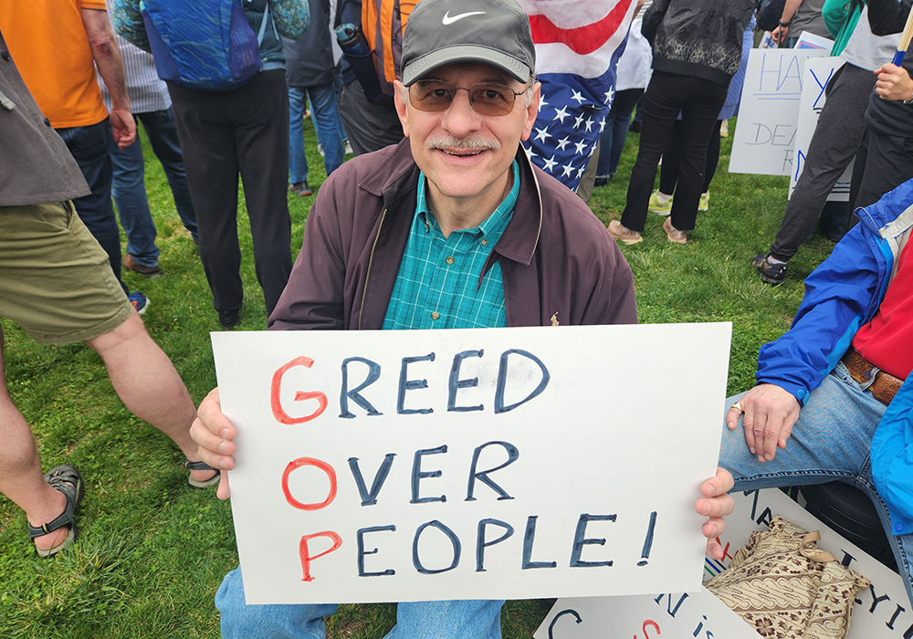 Jim Berlow, a resident of Vienna, Virginia, said he worries about President Trump "destroying the Constitution" and using an "authoritarian playbook to make it happen." He held a sign criticizing the Republican Party, also known as the GOP. (GSR photo/Chris Herlinger)