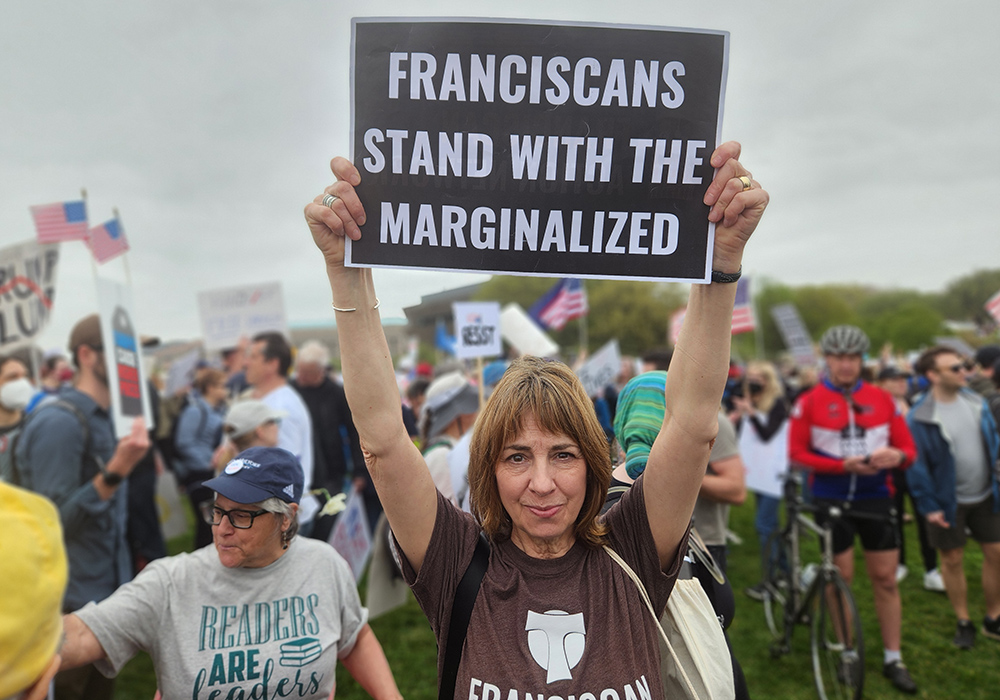 Michele Dunne, the executive director of the Franciscan Action Network, held a sign aloft during the April 5 "Hands Off!" demonstration in Washington, D.C. (GSR photo/Chris Herlinger)
