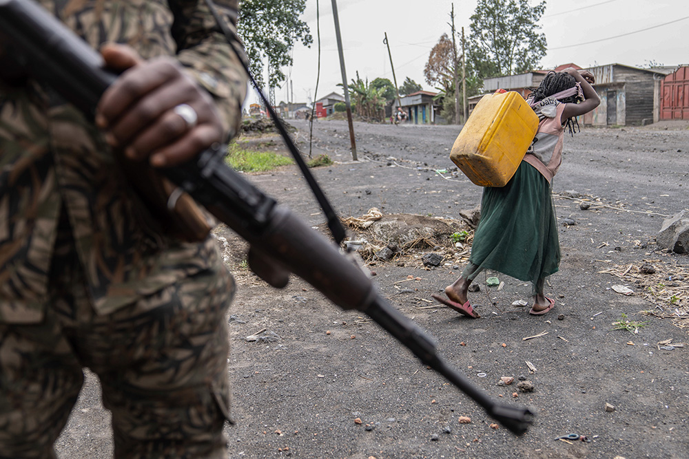 A child carrying water walks past militia forces fighting M23 rebels in Sake, Democratic Republic of the Congo, on Aug. 31, 2024. (AP/Moses Sawasawa)
