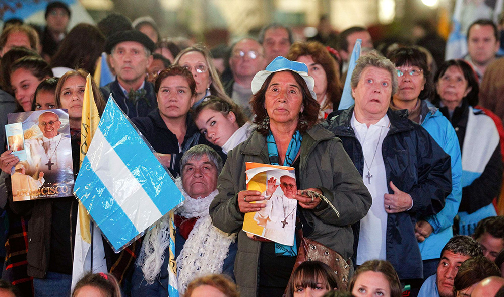 People hold Argentine flags and images of Pope Francis as they watch the televised broadcast of the inaugural Mass of the pontiff on a giant screen outside of the Metropolitan Cathedral in Buenos Aires, Argentina, March 19, 2013. (CNS/Reuters/Marcos Brindicci)