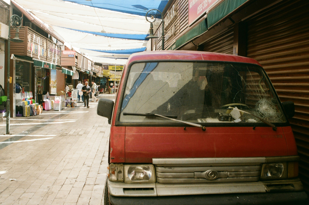 Red van A red van with a cracked windshield parked on the side of the street.