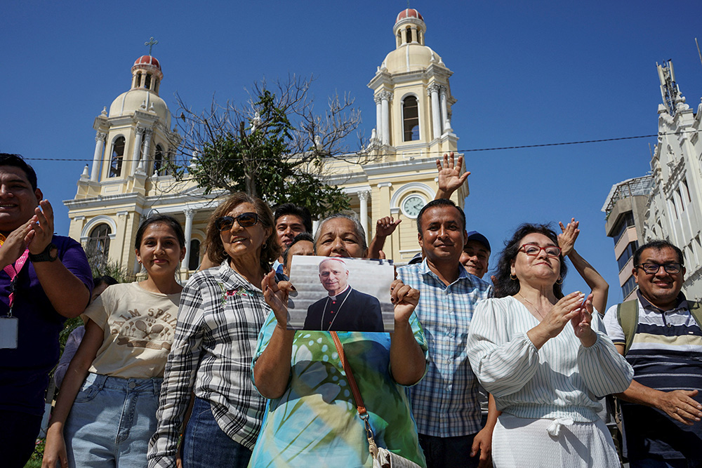 A woman holds an image of then-Cardinal Robert Francis Prevost in front of the Cathedral of St. Mary in Chiclayo, Peru, May 8, 2025, after he was elected the pope at the Vatican and chose the name Leo XIV. As an Augustinian priest, he spent many years as a missionary in Peru. (OSV News/Reuters/Diego Torres Menchola)
