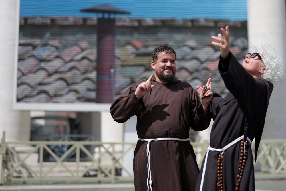 Two male religious react in front of a screen displaying a live feed of the chimney on the Sistine Chapel at the Vatican May 8, 2025, the second day of the conclave to elect the new pope. (OSV News/Reuters/Marko Djurica)