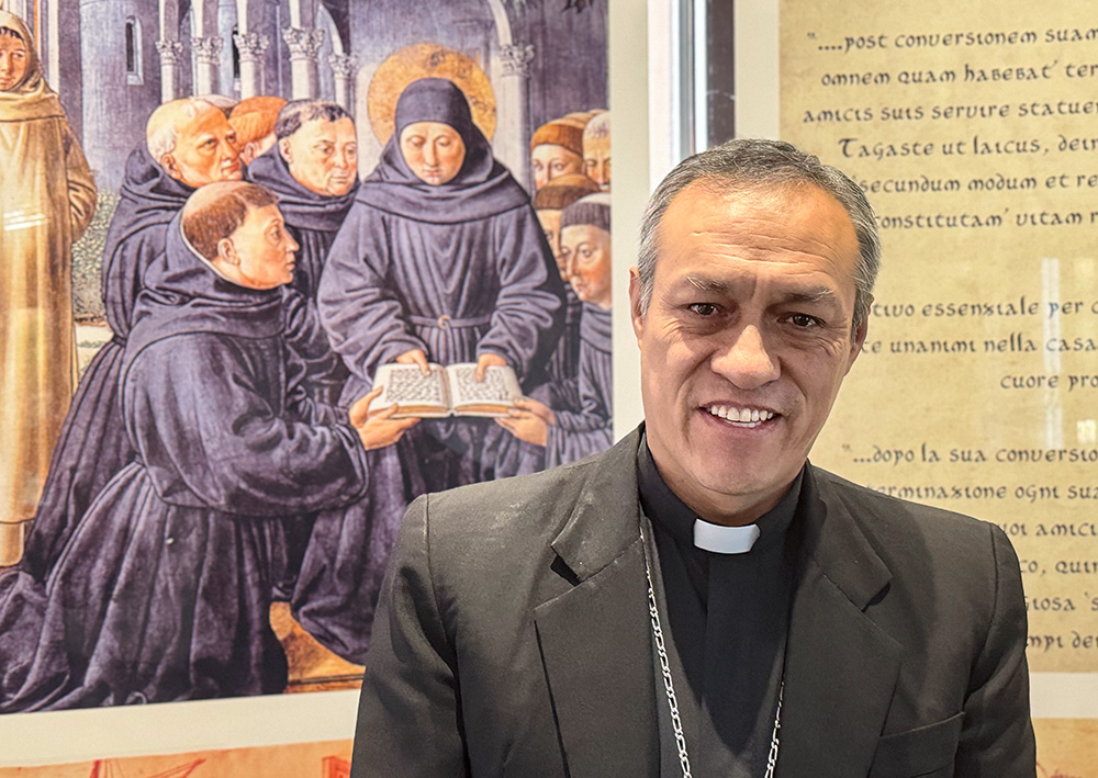 Auxiliary Bishop Lizardo Estrada Herrera of Cuzco, Peru, poses in front of a depiction of St. Augustine in the lobby of the Augustinian curia near St. Peter’s Basilica May 10, 2025. The pope loves Peru and there’s no doubt that life as an Augustinian missionary there shaped him as have other experiences in his life, said Estrada, general secretary of the Latin American Bishops Conference. (GSR photo/ Rhina Guidos)