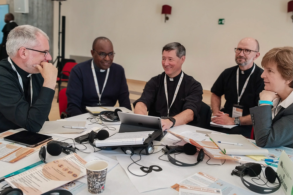 Priests work in an English-language small group April 30, 2024, with facilitator Sr. Maria Cimperman, right, a Religious of the Sacred Heart of Jesus, as part of a meeting of parish priests from around the world gathered at Sacrofano, outside of Rome, to share their experiences and contribute to the ongoing synod on synodality. (CNS/Courtesy of the Synod of Bishops)