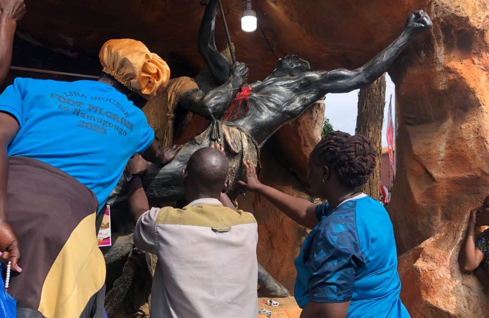 Pilgrims pray in front of a sculpture depicting the brutal execution of a Uganda martyr. Pilgrims pray in front of a sculpture depicting the brutal execution of a Uganda martyr.
