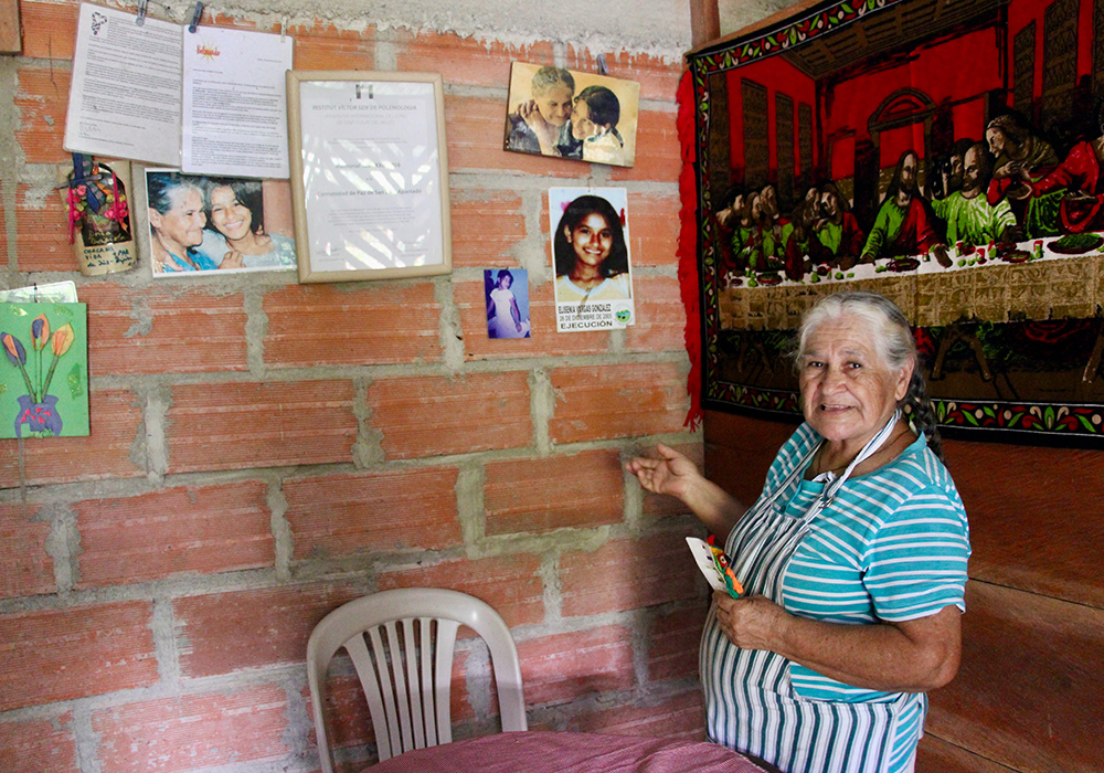 Brígida González of the Peace Community in San José de Apartadó, Colombia, is pictured with her Memory Wall in her home. (Tracy L. Barnett)