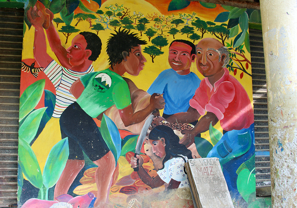 A mural depicts the Peace Community's cooperative work to produce cacao on the side of the bodega. (Tracy L. Barnett)