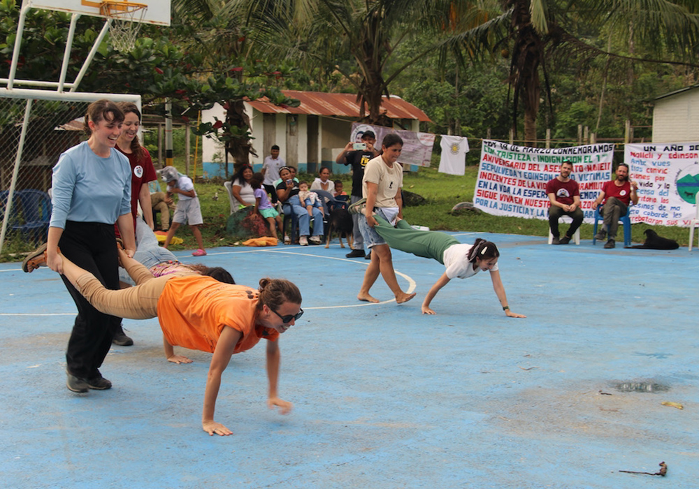 International observers competed with community members in a wheelbarrow race on the cancha during the community's anniversary gathering. (Tracy L. Barnett)