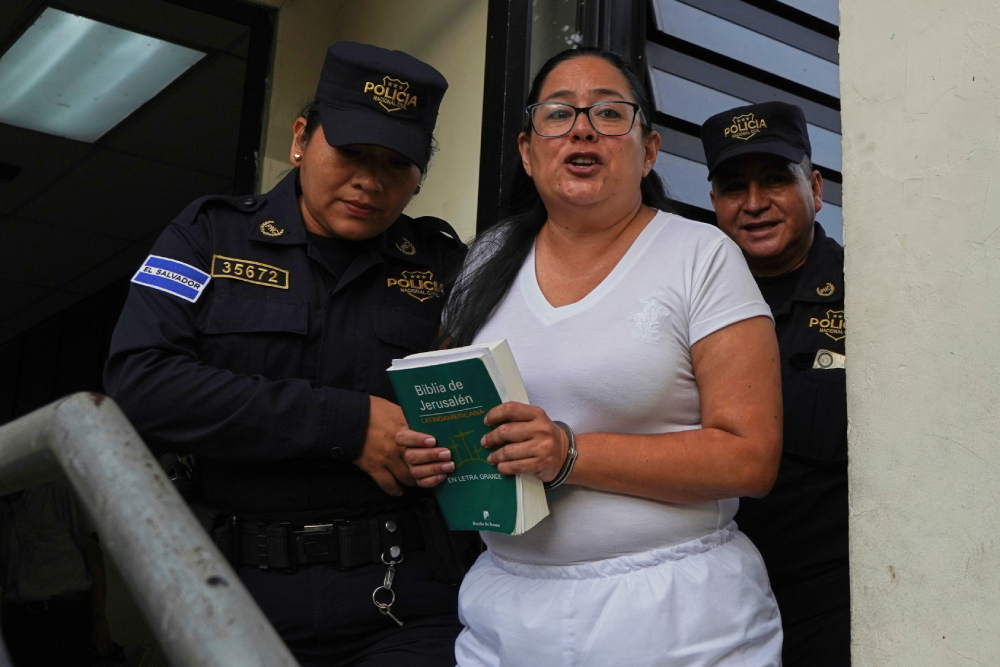 Human rights lawyer Ruth Eleonora Lopez, handcuffed Human rights lawyer Ruth Eleonora Lopez, handcuffed, holds a bible as police escort her out of her court hearing in San Salvador, El Salvador, June 4, 2025. (AP/Salvador Melendez)
