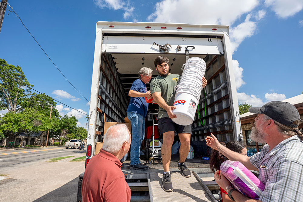 Ethan Clark, a parishioner and volunteer with the Notre Dame Parish relief distribution center in Kerrville, Texas, unloads buckets from a truck of donations that will be used to store the items for emergency cleanup kits. (GSR photo/Gregg Brekke)
