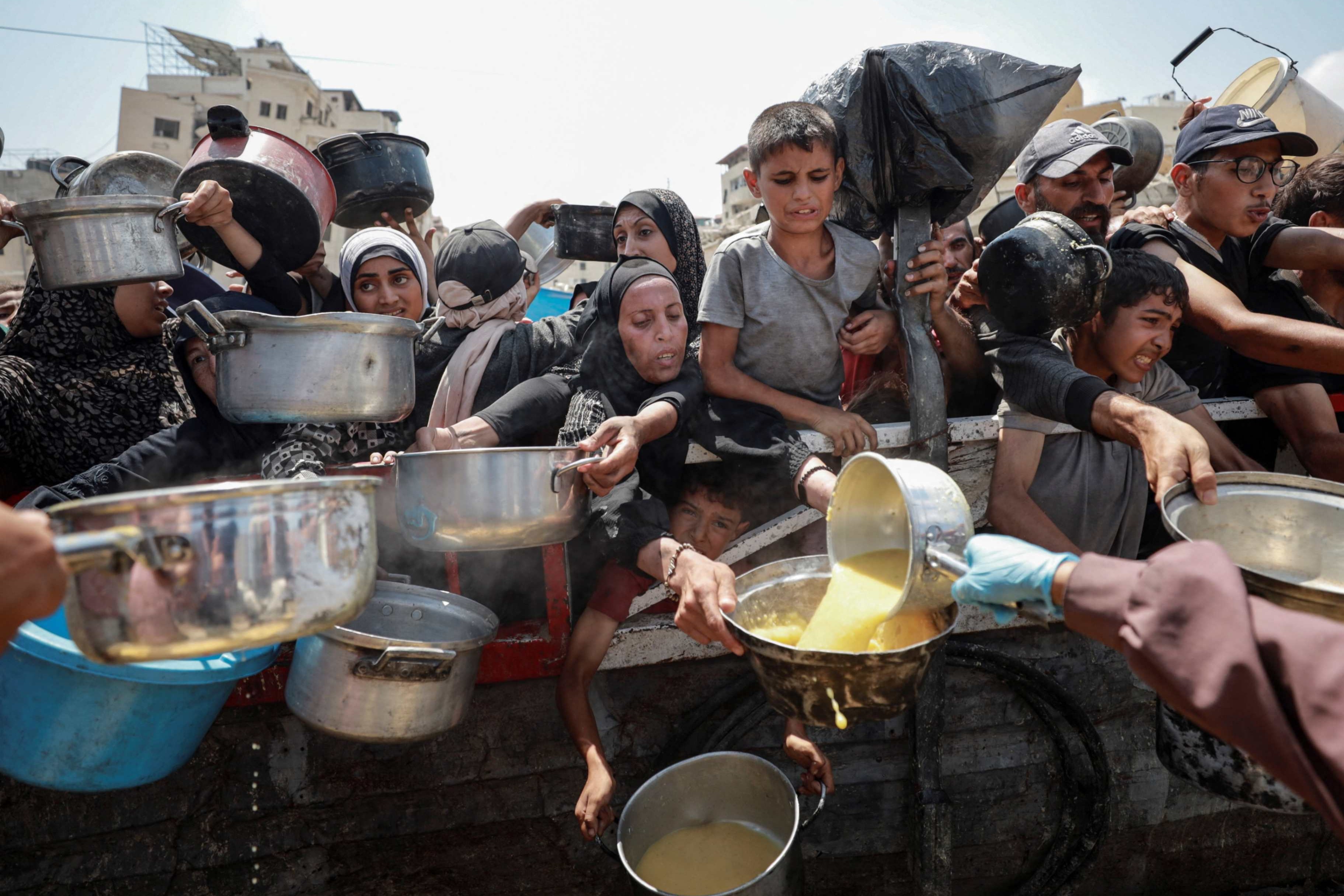 Palestinos reciben comida en un comedor benéfico en la ciudad de Gaza el 28 de julio de 2025, en medio de una crisis de hambre. Jennifer Poidatz, representante interina de Catholic Relief Services (CRS) en Jerusalén, Cisjordania y Gaza, dijo a OSV News el 31 de julio que el personal de CRS en Gaza está trabajando para llevar alimentos altos en calorías y proteínas a los residentes, en medio de tierras agrícolas destruidas, escasez de combustible y energía, precios elevados, peligro y enfermedades. (Foto: OS