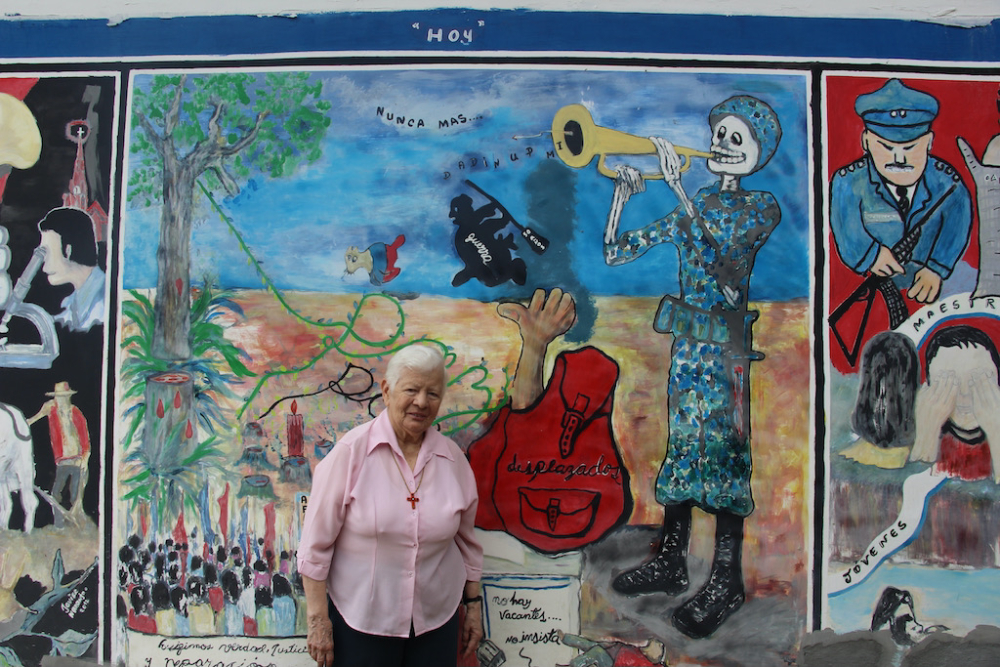 Sr. Maritze Torres explains the "triptica," a mural taking viewers through Trujillo's bloody past (on the right), to its present marked with struggles for justice (center), to its hopeful future, filled with abundance, education, good health and good fortune. (Tracy L. Barnett)