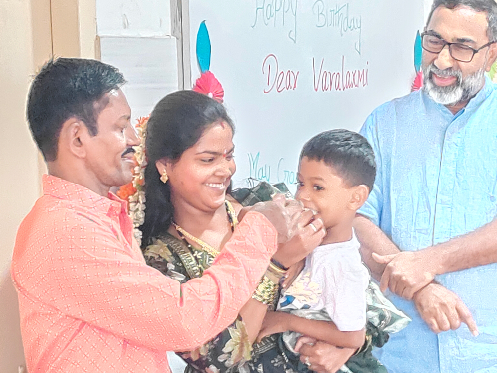 Varalakshmi, a resident of Sumanahalli celebrates her birthday with her husband (left) and daughter. Claretian Fr. George Kannanthanam (right) is also present. (Thomas Scaria) Varalakshmi, a resident of Sumanahalli celebrates her birthday with her husband (left) and daughter. Claretian Fr. George Kannanthanam (right) is also present. (Thomas Scaria)
