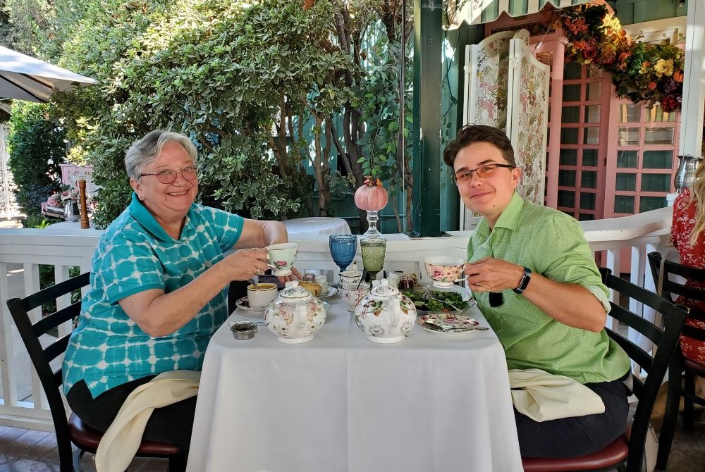 Two women sit at table drinking tea.