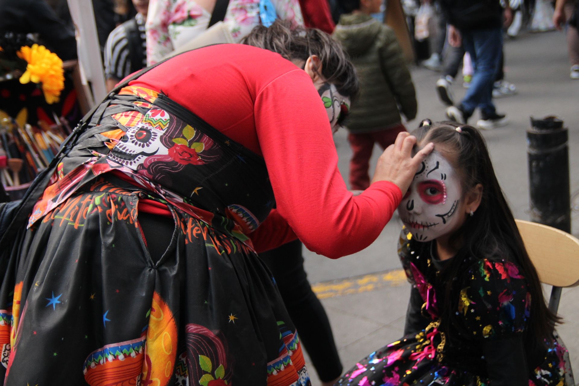 Una mujer maquilla a una niña como catrina en el centro de la Ciudad de México durante el Desfile de las Catrinas. (Foto: Helga Leija/GSR en español)
