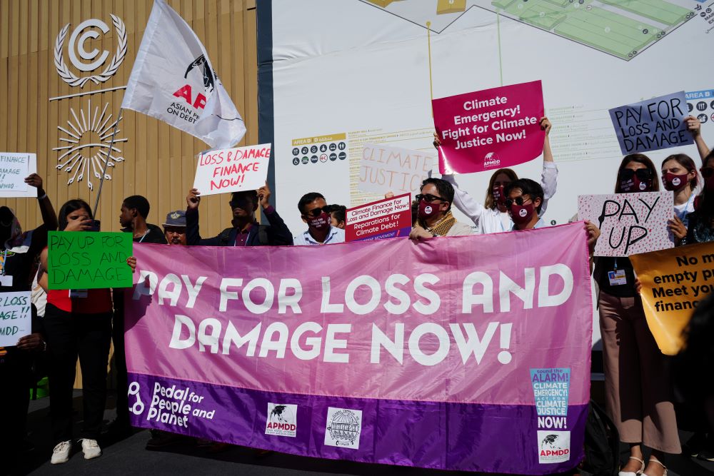 Climate activists hold banner that reads: "Pay for loss and damage now!"