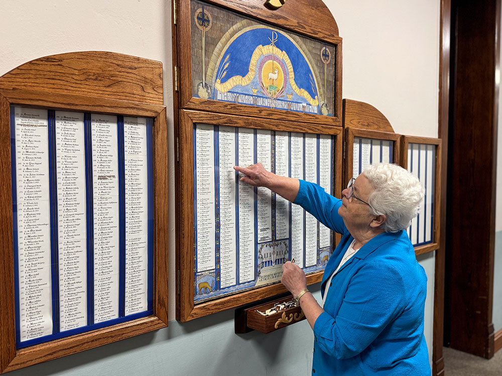 Benedictine Sr. Mary Elizabeth Schweiger draws a number from the necrology board at Mount St. Scholastica, a daily ritual to remember and pray for the sisters who have gone before. As Thanksgiving approaches, this practice deepens gratitude for the women of the Benedictine community of Mount St. Scholastica.(GSR photo/Helga Leija)