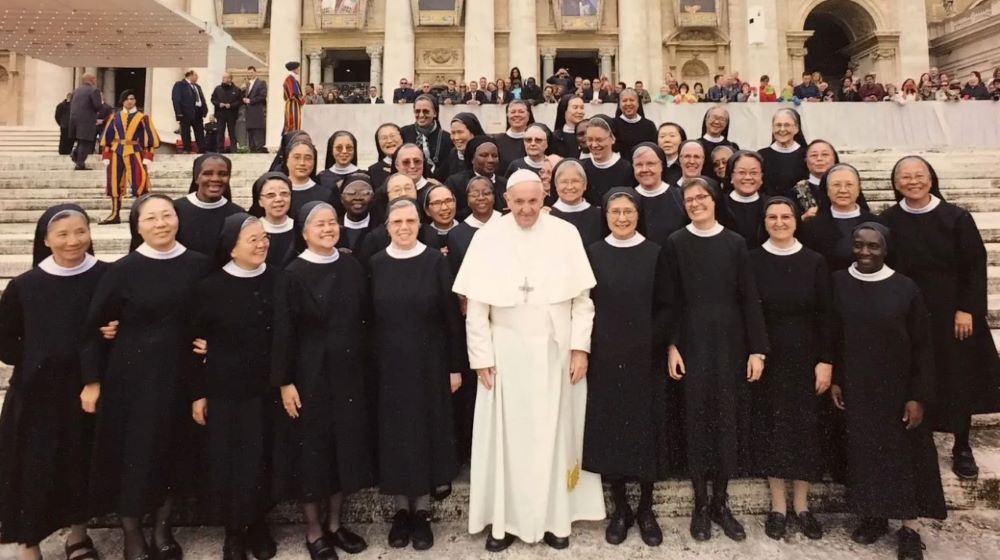 Pope Francis stands with a group of nuns. 