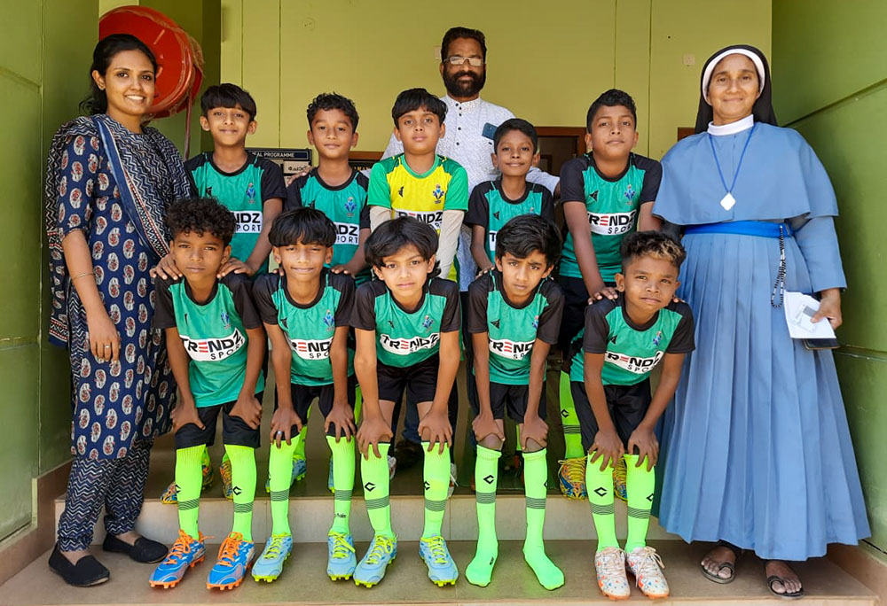 Sr. Sabina Joseph (right) with Shoji Joseph (center), former headmaster of Dwaraka Upper Primary School, and Gralia George (left), physical education teacher, along with the school football team, in Wayanad, Kerala, southwestern India (Courtesy of Sabina Joseph)