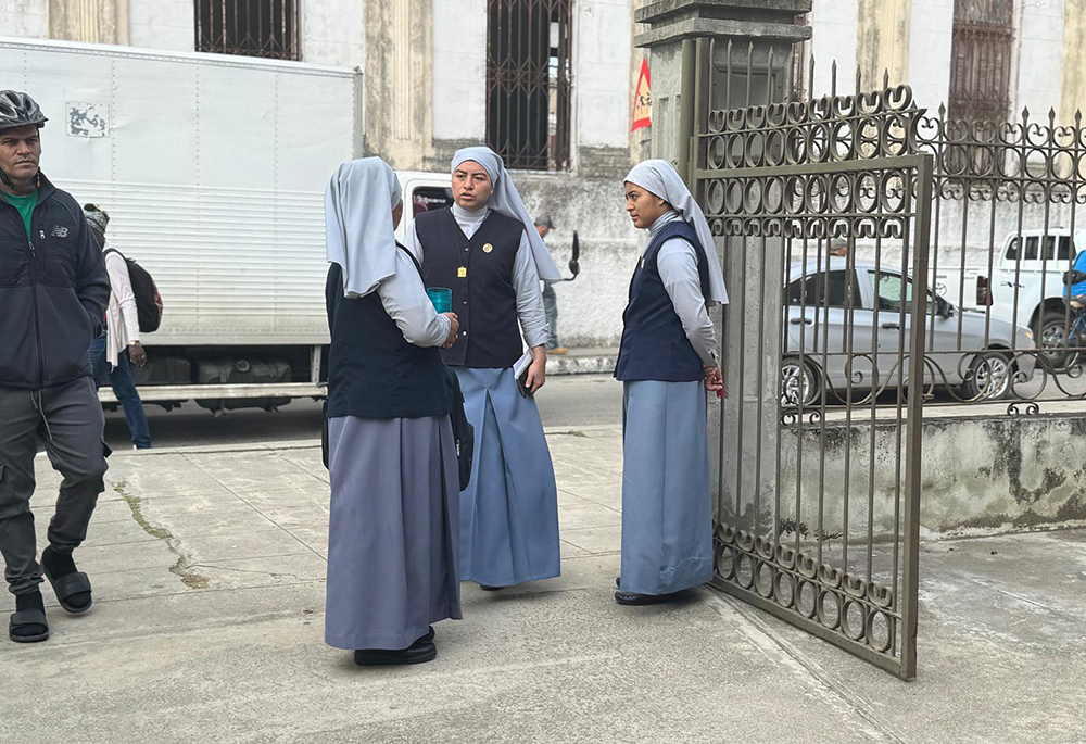 Three missionary sisters from Congregation of Martha and Mary have a conversation Nov. 14, 2025, as people file in to collect potable water from a church in Santa Clara, Cuba. Like the sisters who hail from Guatemala, most members of consecrated life on the island are from outside Cuba, said Auxiliary Bishop Marcos Pirán of the Diocese of Holguín, the head of the Cuban bishops' committee on religious life. (GSR photo/Rhina Guidos)