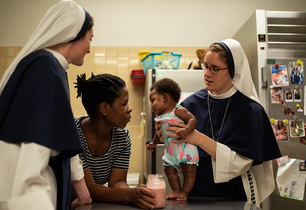 Sr. Faustina Maria Pia and Sr. Maria Veritas play with a mother and child living at the Holy Respite mission in the sisters' convent. (Courtesy of Sr. Catherine Joy Marie)