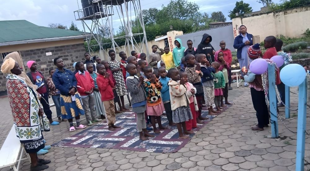 Children at the Holy Family Children's Home in Nakuru, Kenya, pray with Sr. Verah Mwango and other caregivers at the Marian Grotto. (Courtesy of Alphonsa Parathur)