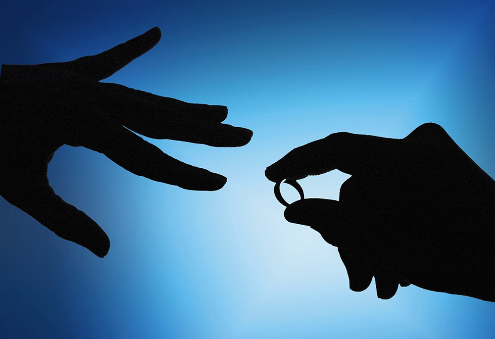 A hand holds a wedding ring in this undated illustration photo. (OSV News/CNS archive/Mike Crupi)