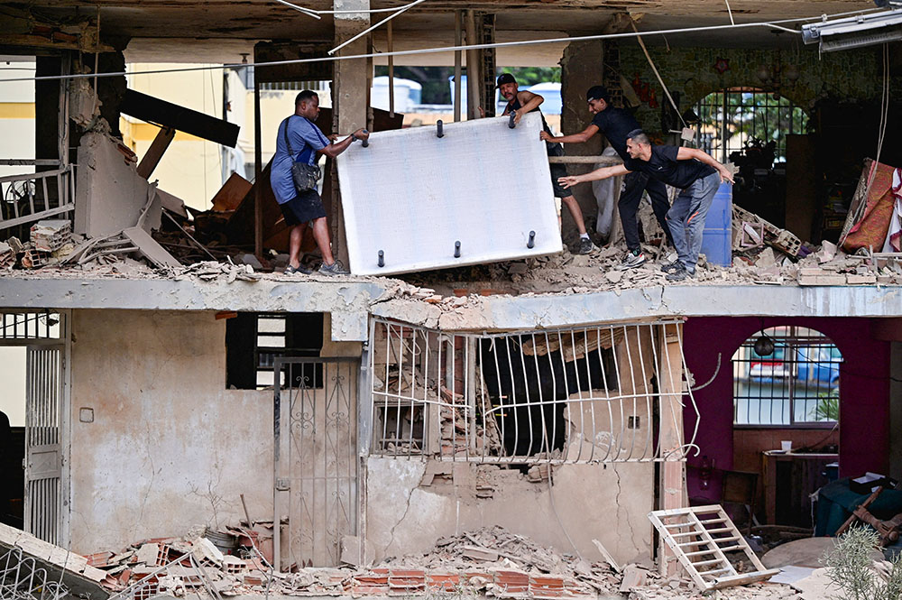 People carry personal belongings at a damaged building in Catia La Mar, Venezuela, Jan. 4, 2026, following U.S. strikes the previous day on Venezuela during which President Nicolas Maduro and his wife, Cilia Flores, were captured. (OSV News/Reuters/Gaby Oraa)