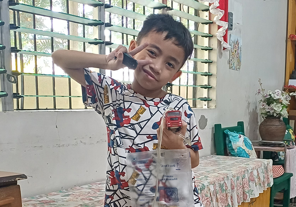 Charls Clyde Amiscal, an 8-year-old who has been living in the sisters' shelter in Quezon City since he was 1, holds his toy jeepney and urine bag. (Oliver Samson)