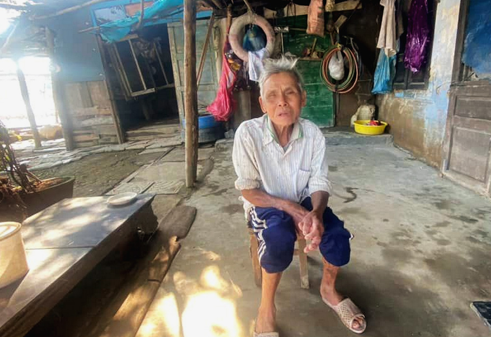 On Dec. 23, 2025, Le Cuoc sits in front of his home in Hue, Vietnam. Its roof was damaged by Typhoon Bualoi. (Joachim Pham)