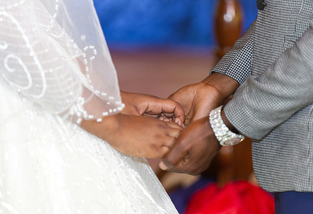 A bride and groom hold hands during a wedding ceremony. (Unsplash/Andrew Itaga)
