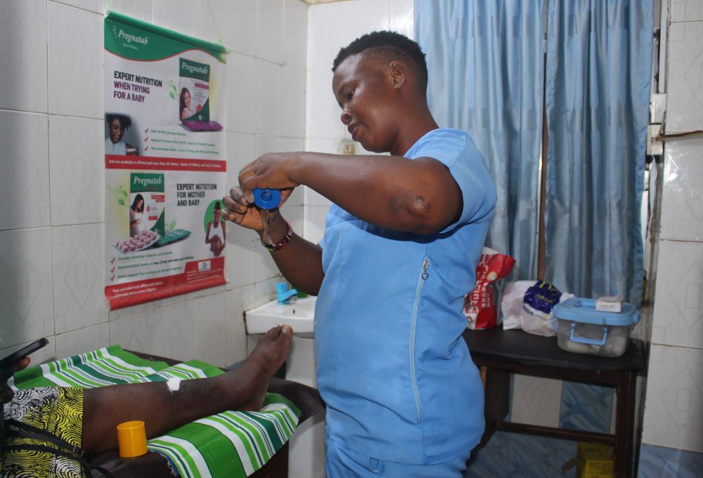 Gladys Madukwe, a nurse-midwife and member of the community advocacy team, dresses a patient's wound in the treatment room at Ancilla Catholic Hospital in Lagos, Nigeria. The hospital is run by the Sisters of the Handmaids of the Holy Child Jesus. (Valentine Benjamin)