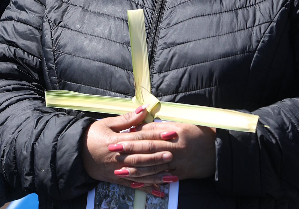 A woman holds a palm frond cross during Palm Sunday Mass outside St. Mary's Chapel at the National Shrine Grotto of Our Lady of Lourdes in Emmitsburg, Md., April 2, 2023. (OSV News/Bob Roller)
