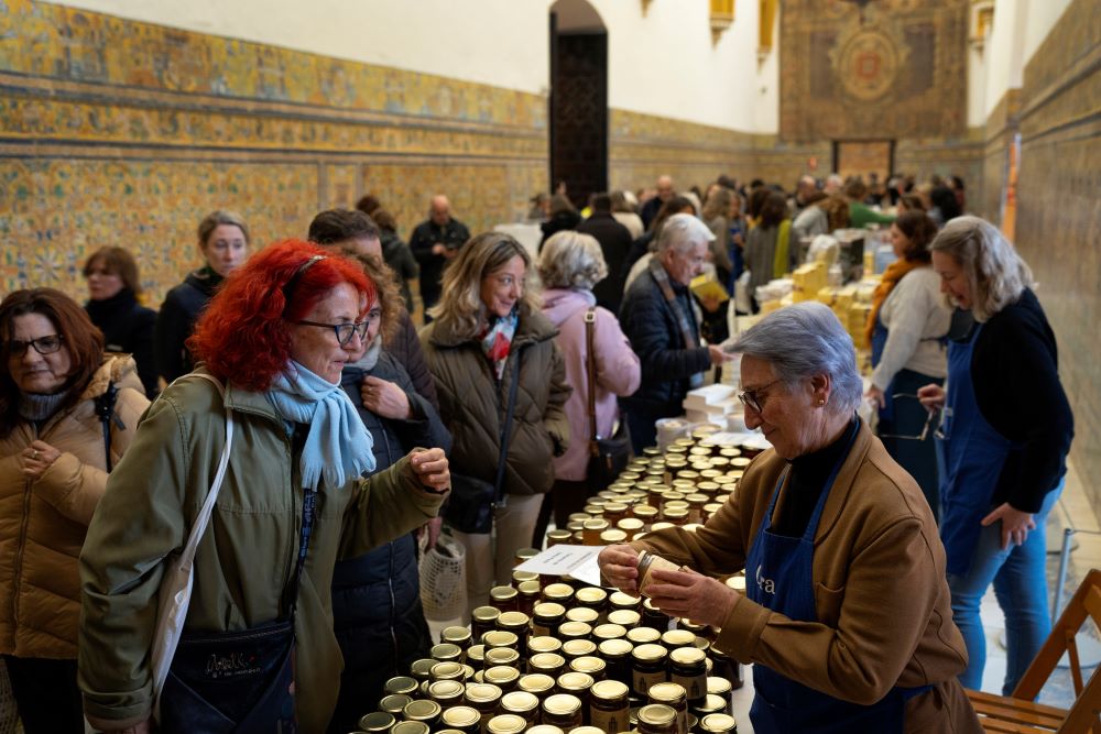 Customers buy marmalades and cakes made by cloistered nuns, at a market at the Reales Alcazares in Seville, Spain, on Dec. 5, 2023. Women's religious communities in Spain are making and selling items, and renting rooms in their monasteries, to generate income. (AP/Laura Leon)