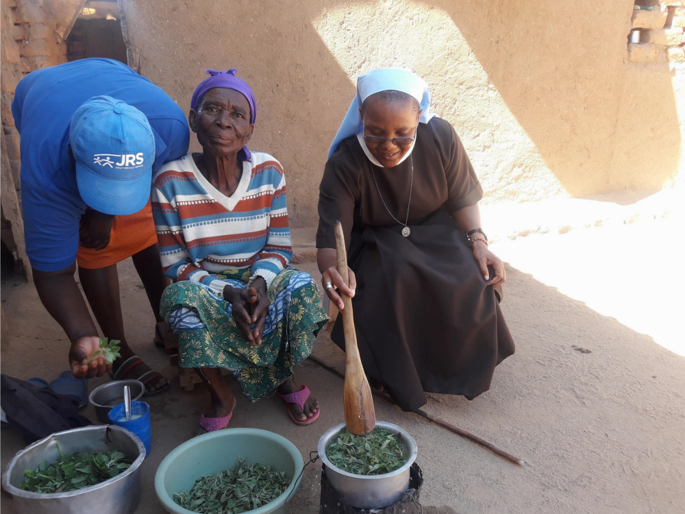 Carmelite Sr. Alice Nyazungu and Jesuit Refuge Service community counselors assist an elderly sick person with cooking in Tongogara Refugee Camp in Zimbabwe in March 2022. (Courtesy of Alice Nyazungu) 