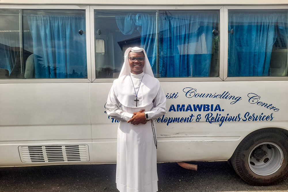 Sr. Maria Adanna Okafor, a Sister of the Immaculate Heart of Mary, Mother of Christ, stands by the bus used at the Mater Christi Human Development and Religious Formation Centre in Amawbia, Nigeria. (John Chukwu)