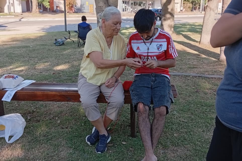 En febrero de 2026, en una plaza de Villa Ramallo, jóvenes y mayores tejieron juntos la palabra paz, entre mate, lana y conversación, como gesto concreto de encuentro y hermandad. (Foto: cortesía Susana Pasqualini)