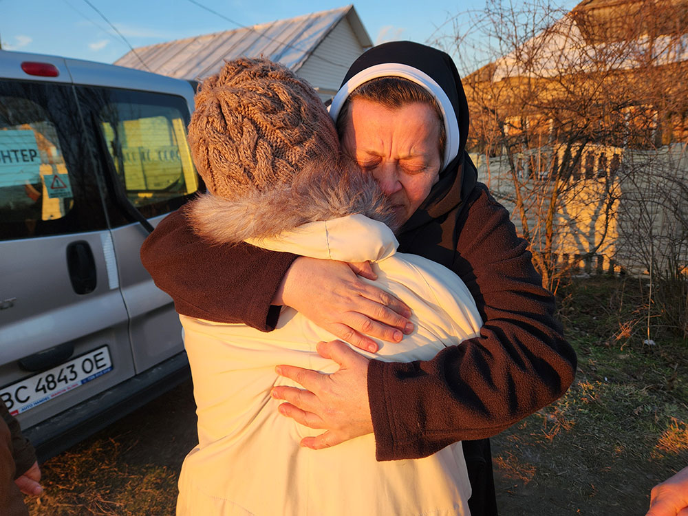 Sr. Lucia Murashko, a member of the Order of St. Basil the Great, hugs a resident of the village of Orihiv, eastern Ukraine, during a delivery of humanitarian supplies in February 2024. (GSR photo/Chris Herlinger)