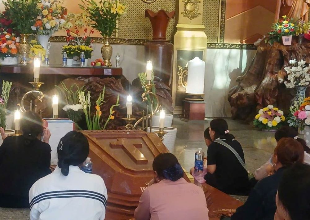 Vietnamese faithful pray beside the grave of Fr. Francis Xavier Truong Buu Diep at Tac Say Pilgrimage Center in southern Vietnam. Father Francis, a martyr, is to be canonized as a Catholic saint on July 2 at the center. (Courtesy of Mary Nguyen)