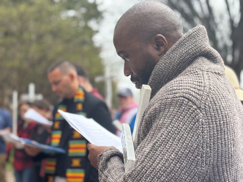 Steven Nabieu Rogers, of the Africa Faith and Justice Network, prays while holding a cross outside the U.S. Department of Justice in Washington April 3, 2026, during the Way of the Cross on Good Friday. It feels as if the institutions of governance are not carrying out their role and as Catholics, there’s a need to pray about that, he said. (NCR photo/Rhina Guidos) 