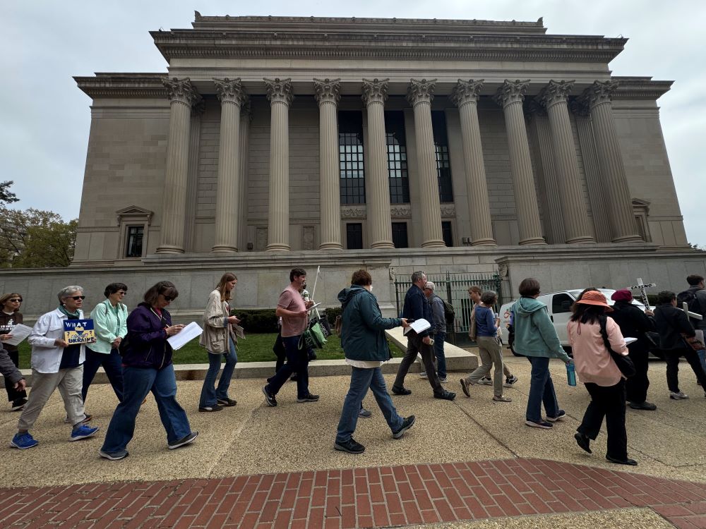 A group of Catholics and others sing as they walk past the National Archives building in Washington during the Way of the Cross on Good Friday April 3, 2026. The event includes what organizers describe as modern-day crucifixions such as wealth disparity, violence against migrants and the erosion of peace efforts. (NCR photo/Rhina Guidos)