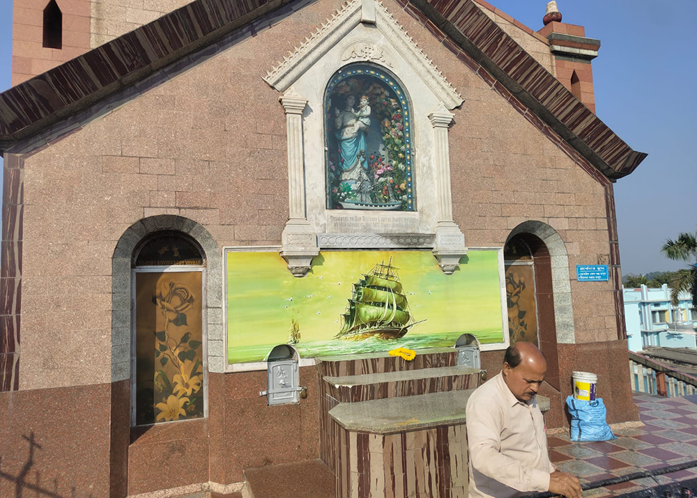 A volunteer cleans a candle stand in front of the statue of Our Lady of Happy Voyage at the Basilica of the Holy Rosary at Bandel, West Bengal state. (George Kommathil)