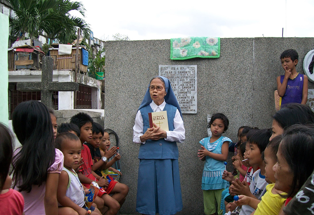 Sr. Evangelina Canag teaches Bible lessons to children living inside a public cemetery in Manila in 2008. (Courtesy of Daughters of St. Paul)