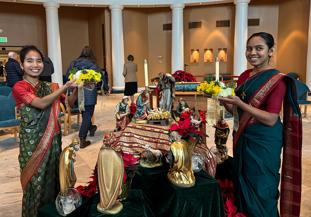Srs. Sagorika Tripura and Shimu Lindouar offer the aroti, a solemn blessing during liturgies that uses marigolds and other flowers, candles and incense. (Courtesy of Suzanne Patterson)